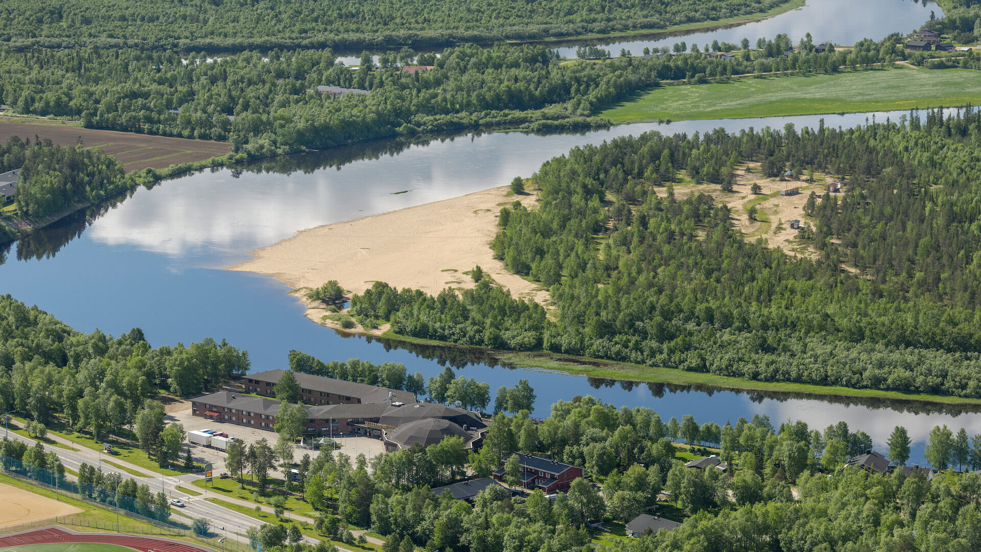 Hotelli Ivalo yläilmoista kuvattuna. Maisemassa näkyy metsää, joki ja jokisuisto.