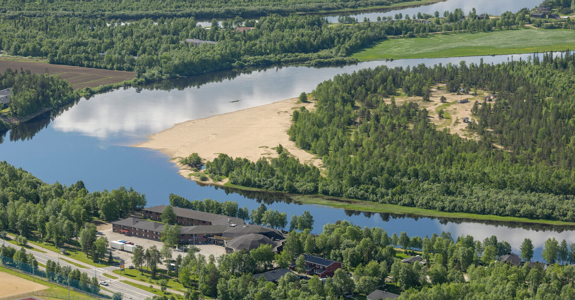 Hotelli Ivalo yläilmoista kuvattuna. Maisemassa näkyy metsää, joki ja jokisuisto.