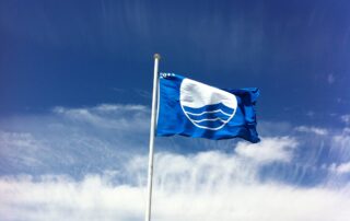Blue Flag -lippu liehuu sinistä taivasta ja valkoisia pilvenhaituvia vasten.