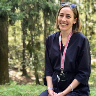 Ohjelmajohtaja Heidi Heinonen hymyilee metsäisessä ympäristössä.