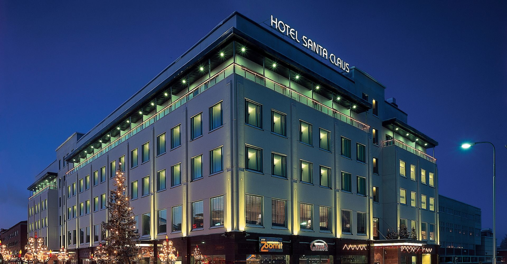 Kuvassa on Santa's Hotel Santa Claus hotelli pimeässä, katuvaloin valaistussa Rovaniemen kaupungissa.