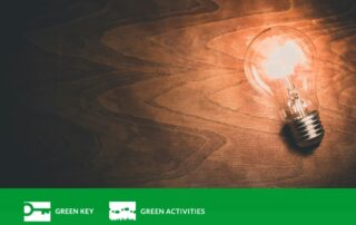 Puista taustaa kirkkaana hehkuva hehkulamppu.