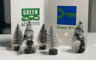 Green Key ja Green Activities -sertifikaattikannet pöydällä joulukoristeiden lomassa.