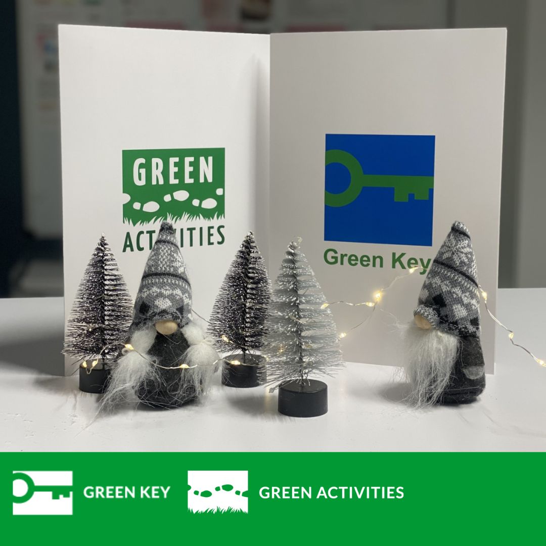 Green Key ja Green Activities -sertifikaattikannet pöydällä joulukoristeiden lomassa.