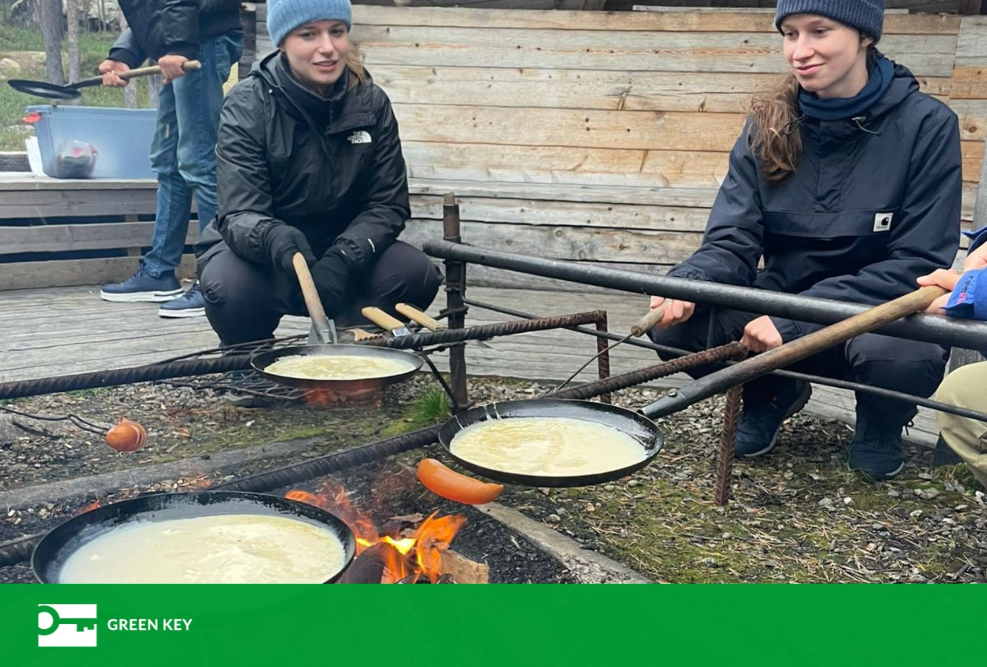 Kaksi nuorta paistamassa muurinpohjalettuja nuotiolla
