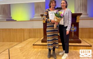 Kuvassa Taiga Timesin Kiia poseeraa Vuoden matkailuyritys -diplomin ja kukkakimpun kera, vierellään Going Greenin ohjelmajohtaja Heidi Heinonen.